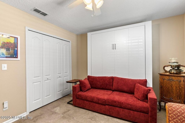 living area featuring visible vents, a ceiling fan, and baseboards