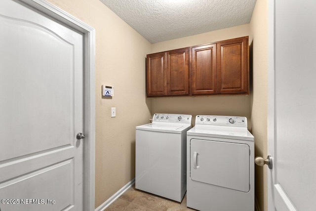 laundry room featuring cabinet space, independent washer and dryer, a textured ceiling, and baseboards