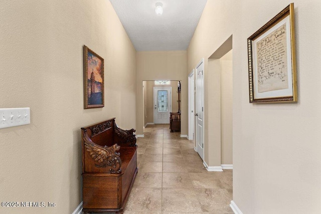 corridor with baseboards and light tile patterned flooring