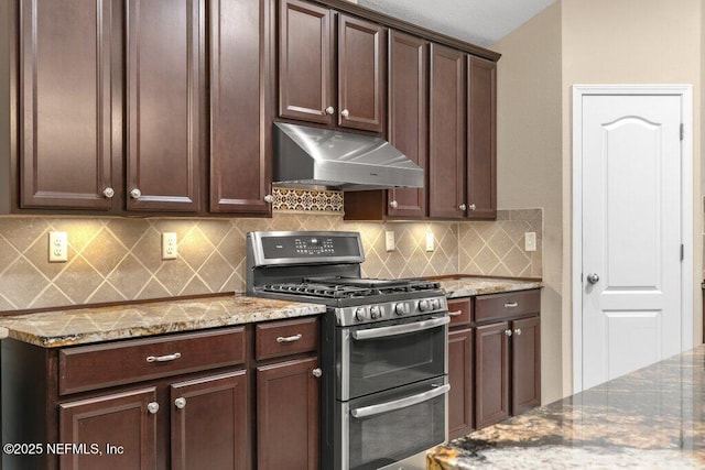 kitchen featuring dark brown cabinetry, under cabinet range hood, tasteful backsplash, light stone counters, and range with two ovens