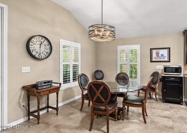 dining room with baseboards, a notable chandelier, vaulted ceiling, and a wealth of natural light