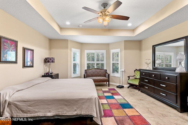 bedroom featuring recessed lighting, a tray ceiling, a ceiling fan, and baseboards