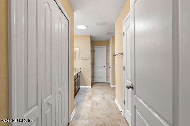 hallway with baseboards and a textured ceiling
