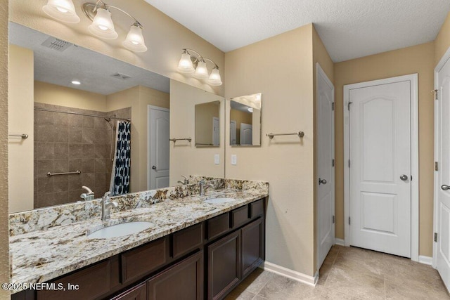 full bath with a sink, baseboards, tiled shower, and visible vents