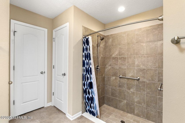 full bathroom featuring tile patterned flooring, a shower stall, and a textured ceiling