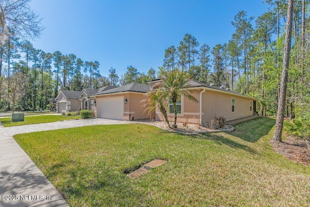 view of front of home featuring an attached garage, stucco siding, decorative driveway, and a front yard