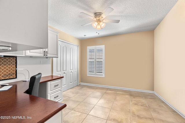 unfurnished office with a ceiling fan, a textured ceiling, light tile patterned flooring, and baseboards