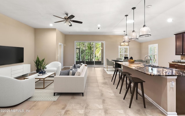 living room with baseboards, ceiling fan, recessed lighting, and a wealth of natural light