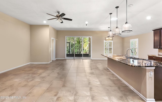 kitchen with dark stone counters, open floor plan, a wealth of natural light, and a sink