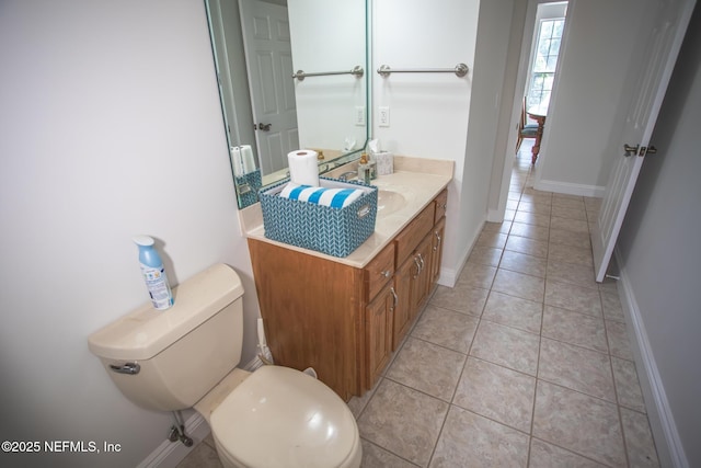 half bath featuring toilet, tile patterned flooring, vanity, and baseboards