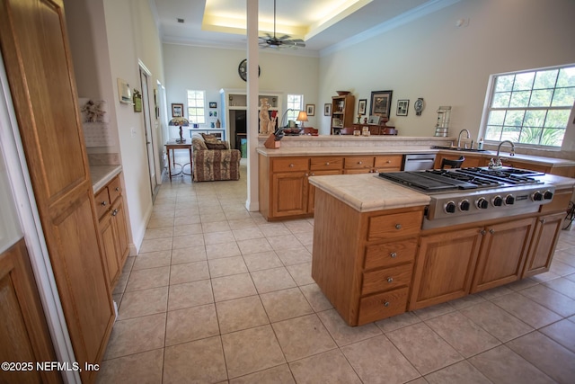 kitchen with stainless steel gas stovetop, light tile patterned flooring, a tray ceiling, crown molding, and a ceiling fan