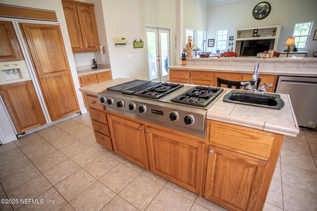 kitchen with light tile patterned floors, appliances with stainless steel finishes, a sink, open floor plan, and french doors