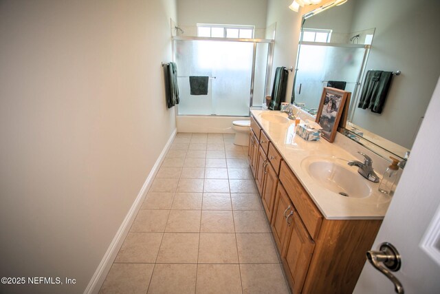 bathroom featuring a sink, toilet, double vanity, baseboards, and tile patterned flooring