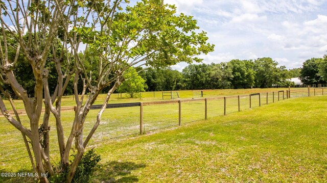 view of yard with fence and a rural view