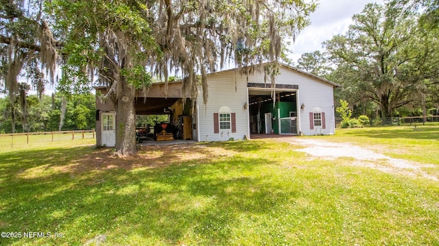 rear view of house with an outdoor structure, a pole building, fence, a yard, and a garage