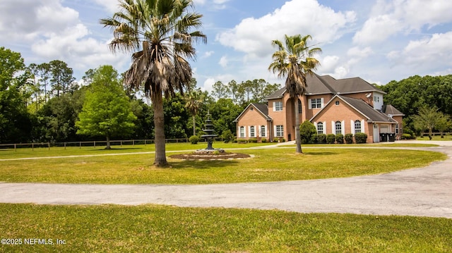 colonial home featuring fence, driveway, a front lawn, and a garage