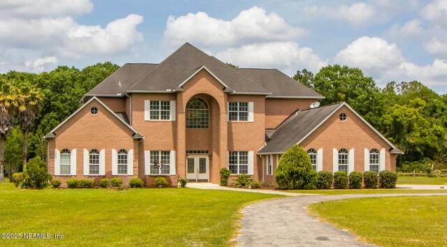 colonial-style house featuring brick siding, french doors, and a front yard