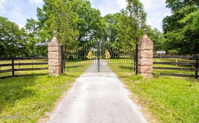 view of gate featuring fence and a lawn