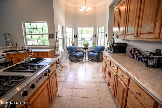 kitchen featuring light tile patterned floors, a sink, appliances with stainless steel finishes, tile countertops, and a high ceiling