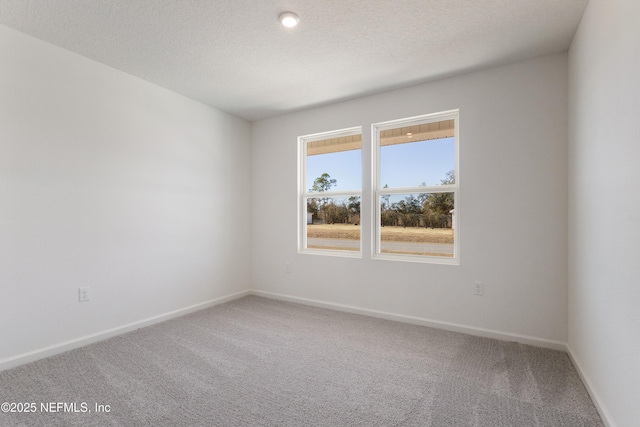 carpeted empty room with baseboards and a textured ceiling