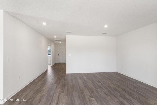 empty room featuring baseboards, dark wood-type flooring, and recessed lighting