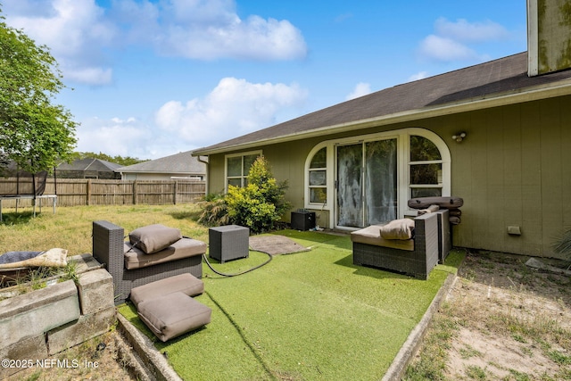view of yard featuring a trampoline, fence, and central AC unit