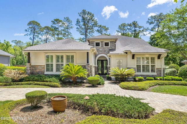 view of front of home with roof with shingles, french doors, stone siding, and stucco siding