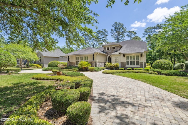 view of front facade featuring stucco siding, a front lawn, decorative driveway, and stone siding