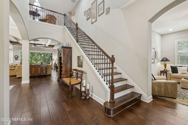 stairs featuring plenty of natural light, arched walkways, ceiling fan, and wood-type flooring