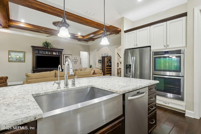 kitchen with light stone countertops, appliances with stainless steel finishes, a sink, dark wood finished floors, and open floor plan