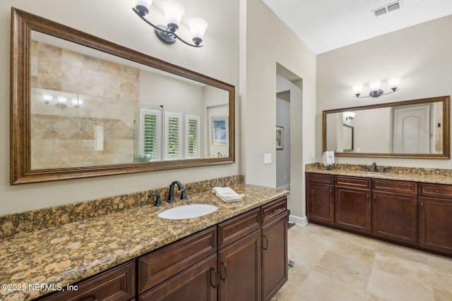 full bathroom with a sink, two vanities, a tile shower, and visible vents