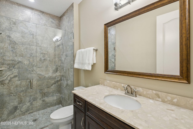 bathroom featuring vanity, toilet, and tiled shower