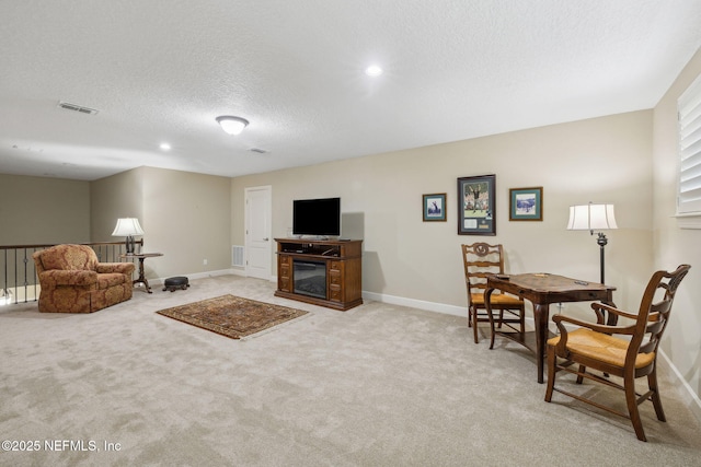 living area featuring a textured ceiling, visible vents, light carpet, and baseboards