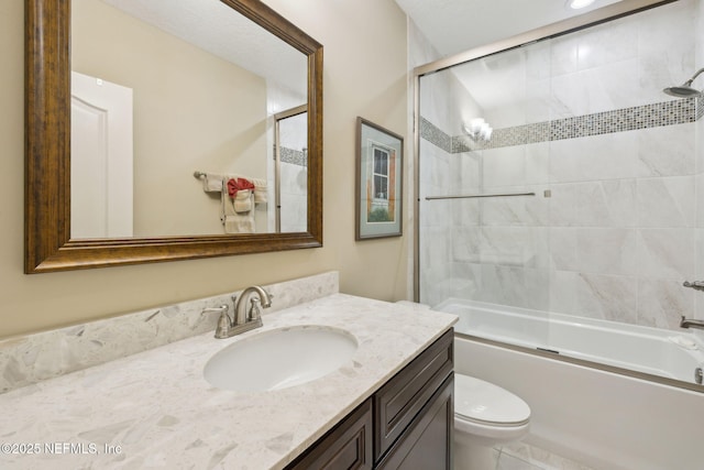 bathroom featuring toilet, bath / shower combo with glass door, and vanity