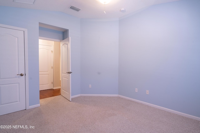 empty room featuring carpet floors, baseboards, visible vents, and vaulted ceiling