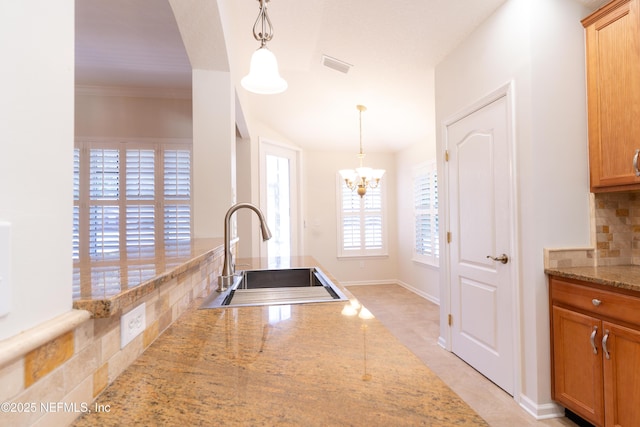kitchen featuring decorative light fixtures, a notable chandelier, decorative backsplash, and a sink