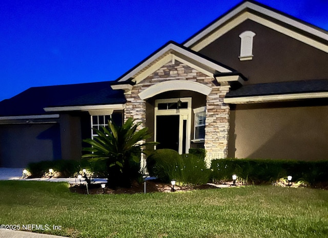view of front of home featuring a lawn, stucco siding, and stone siding