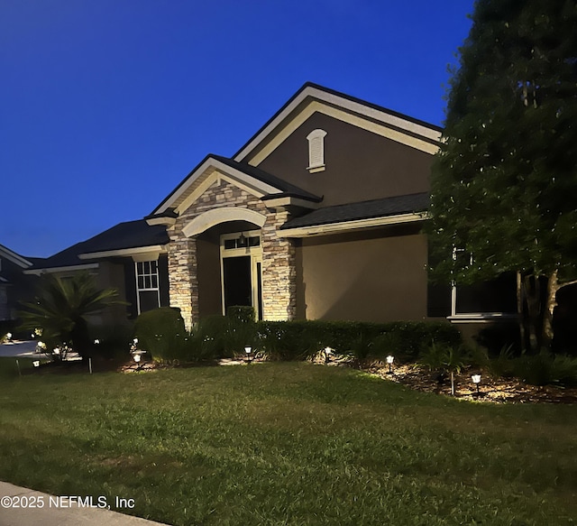 single story home featuring a lawn, stone siding, and stucco siding