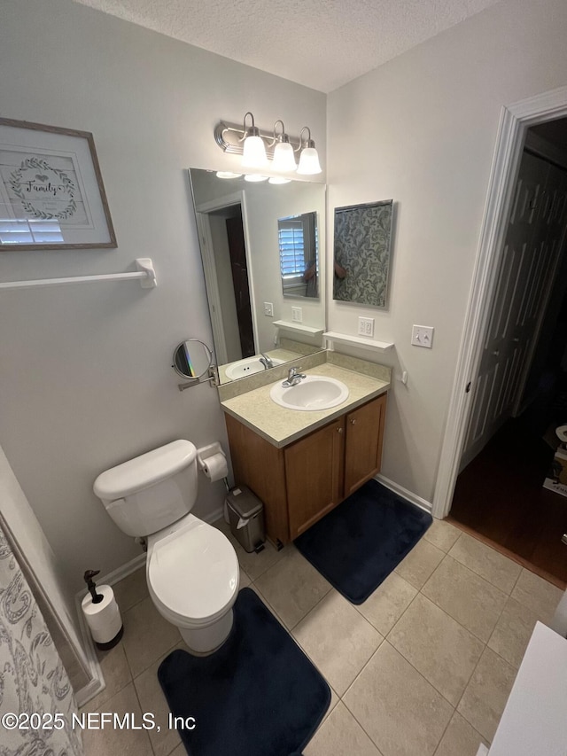 bathroom featuring toilet, tile patterned floors, a textured ceiling, and vanity