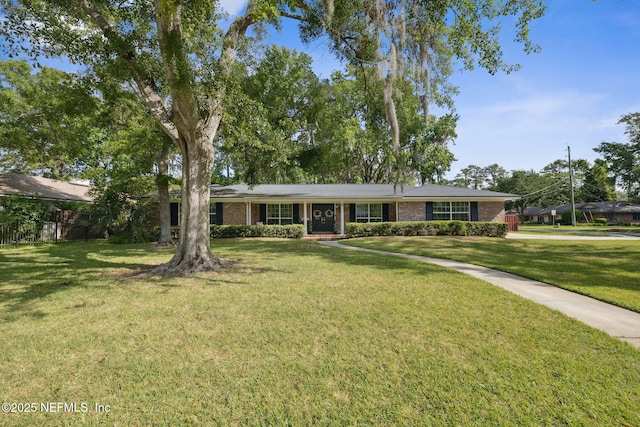 ranch-style home featuring brick siding, fence, and a front yard