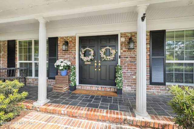 property entrance with covered porch and brick siding