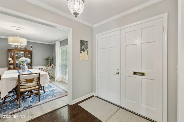 entrance foyer with baseboards, ornamental molding, dark wood-style flooring, and a chandelier
