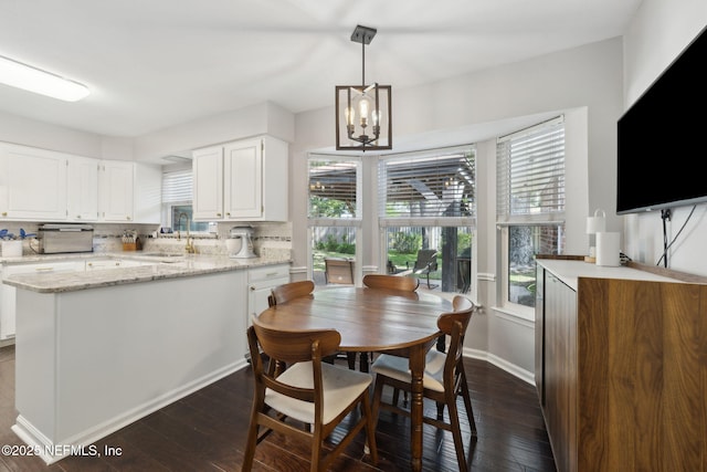 dining room featuring dark wood-style flooring, baseboards, and an inviting chandelier