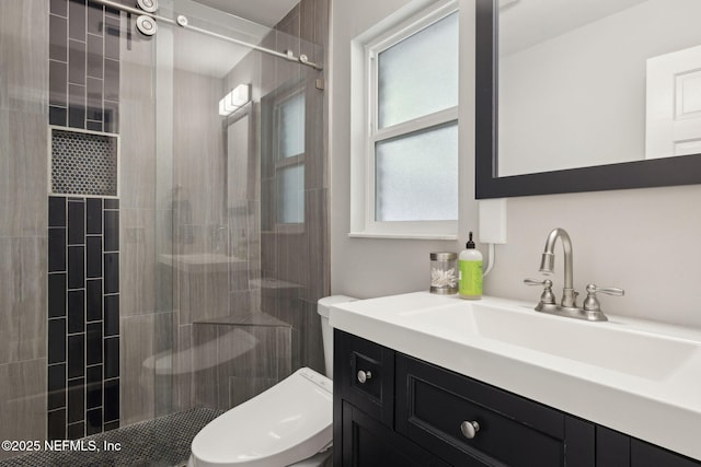full bath with toilet, tiled shower, and vanity