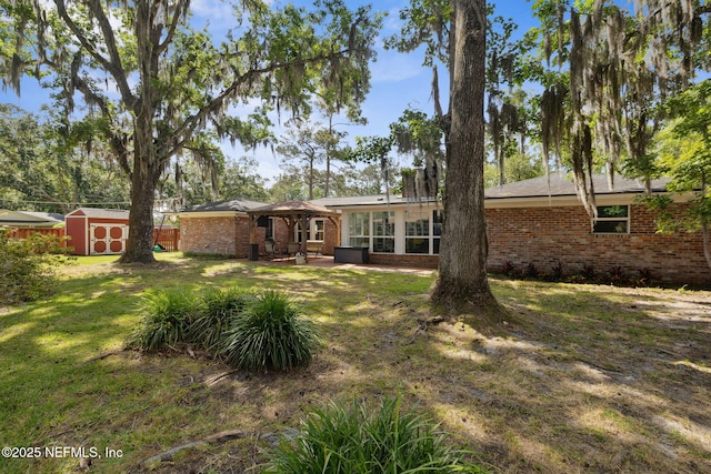 back of property featuring a storage shed, brick siding, a patio, and a lawn