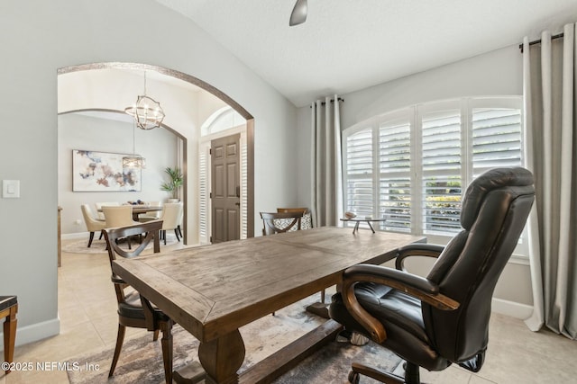 dining room with lofted ceiling, light tile patterned flooring, arched walkways, baseboards, and a notable chandelier