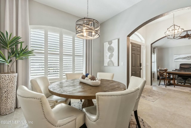 dining space with light tile patterned flooring, arched walkways, and an inviting chandelier