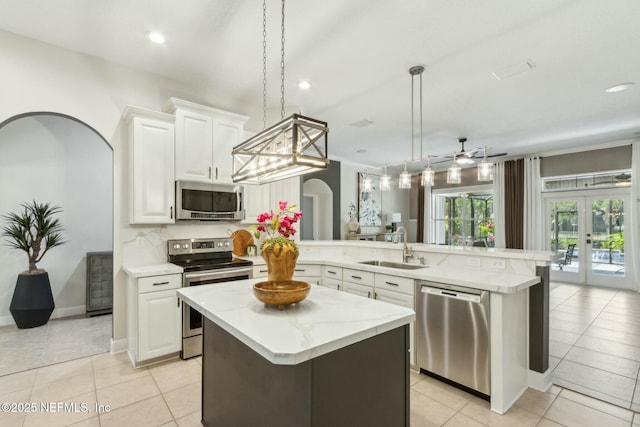 kitchen featuring light tile patterned floors, a sink, a peninsula, and stainless steel appliances