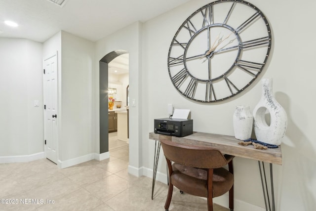 office space with baseboards, light tile patterned floors, and arched walkways