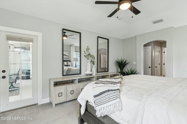 bedroom featuring arched walkways, baseboards, visible vents, light colored carpet, and a ceiling fan
